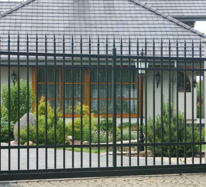 stalowa brama wjazdowa przed eleganckim domem z ogrodem